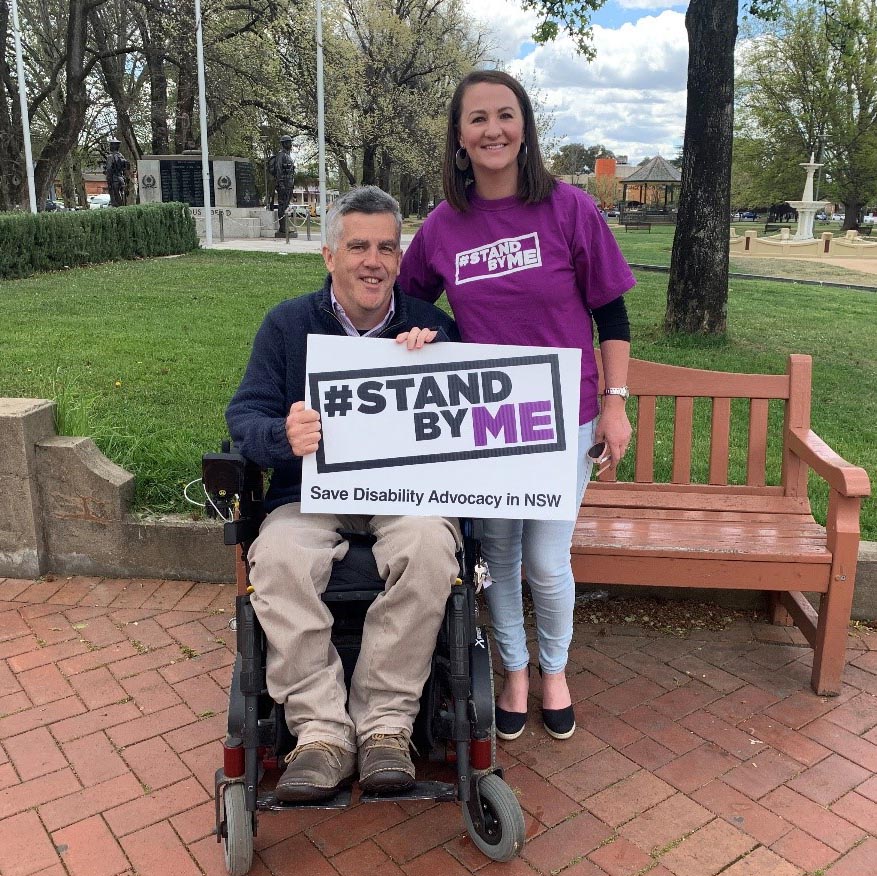Glenn Cairns with Eveleen May from Disability Advocacy NSW, holding a Stand By Me sign